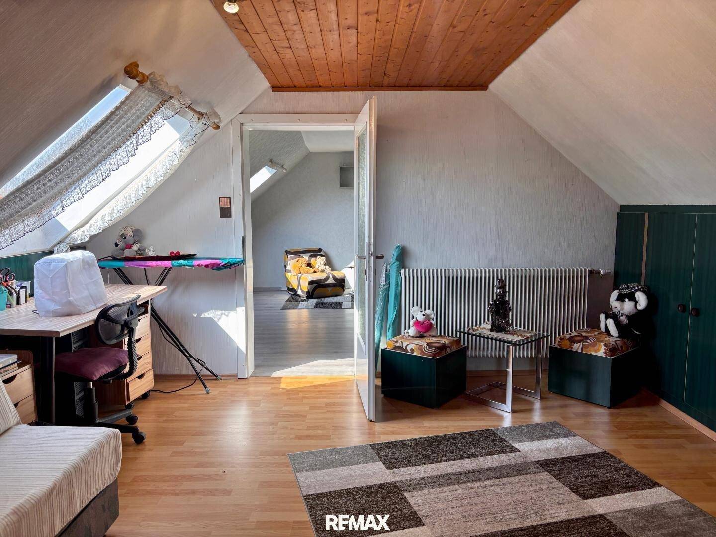 Dachzimmer als Büro genutzt mit Dachfenster und Holzdecke.