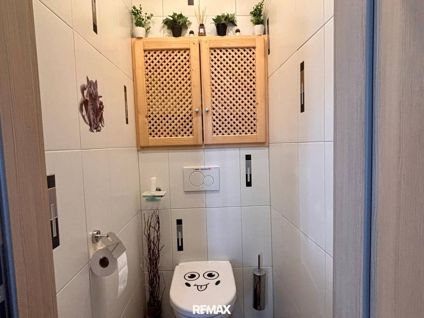 Separate Toilette mit Wand-WC und Holzschrank.