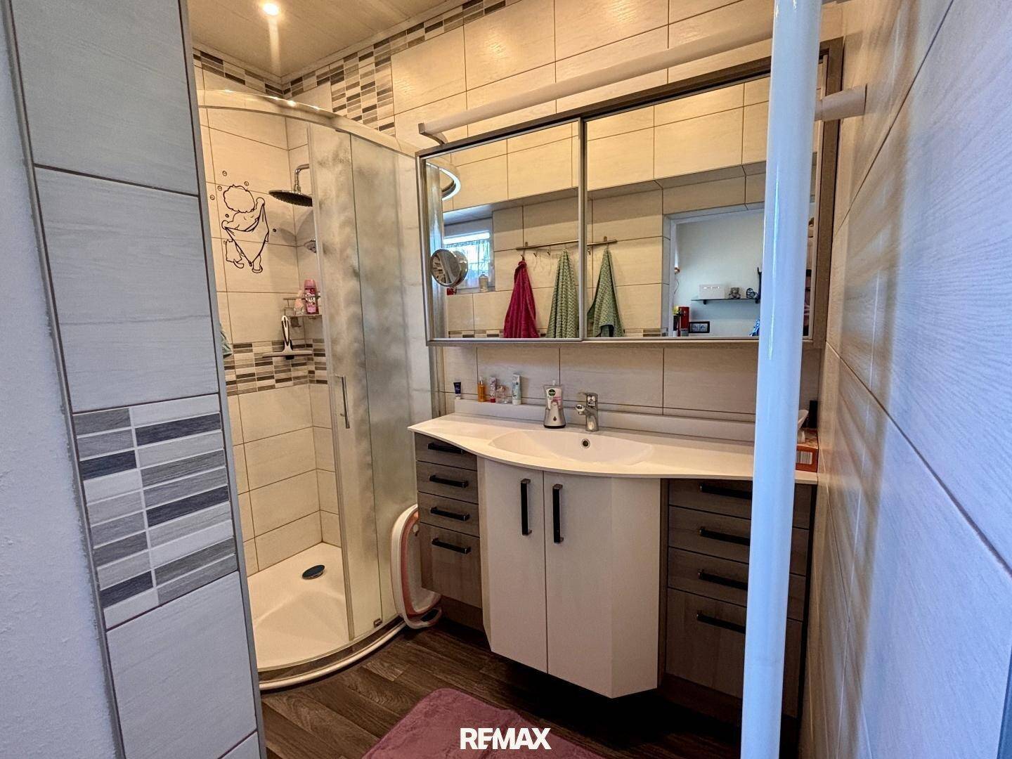 Badezimmer mit Duschkabine, Waschbecken und Spiegelschrank.