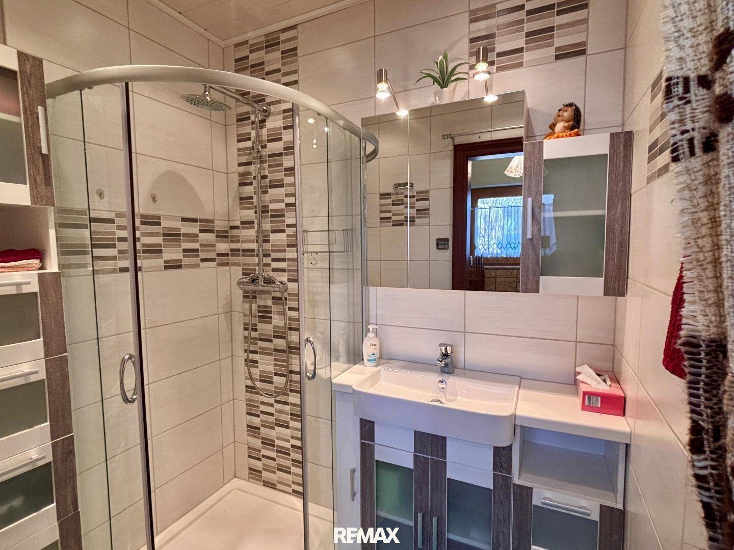 Badezimmer mit Duschkabine, Waschbecken und Spiegelschrank.