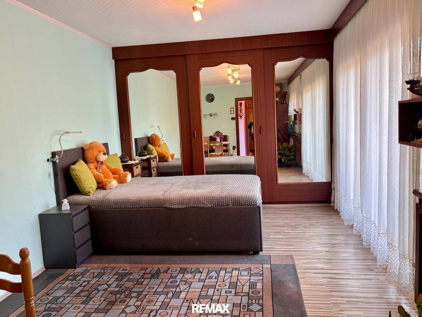 Schlafzimmer mit großem Bett, Spiegelschränken und hellem Boden.