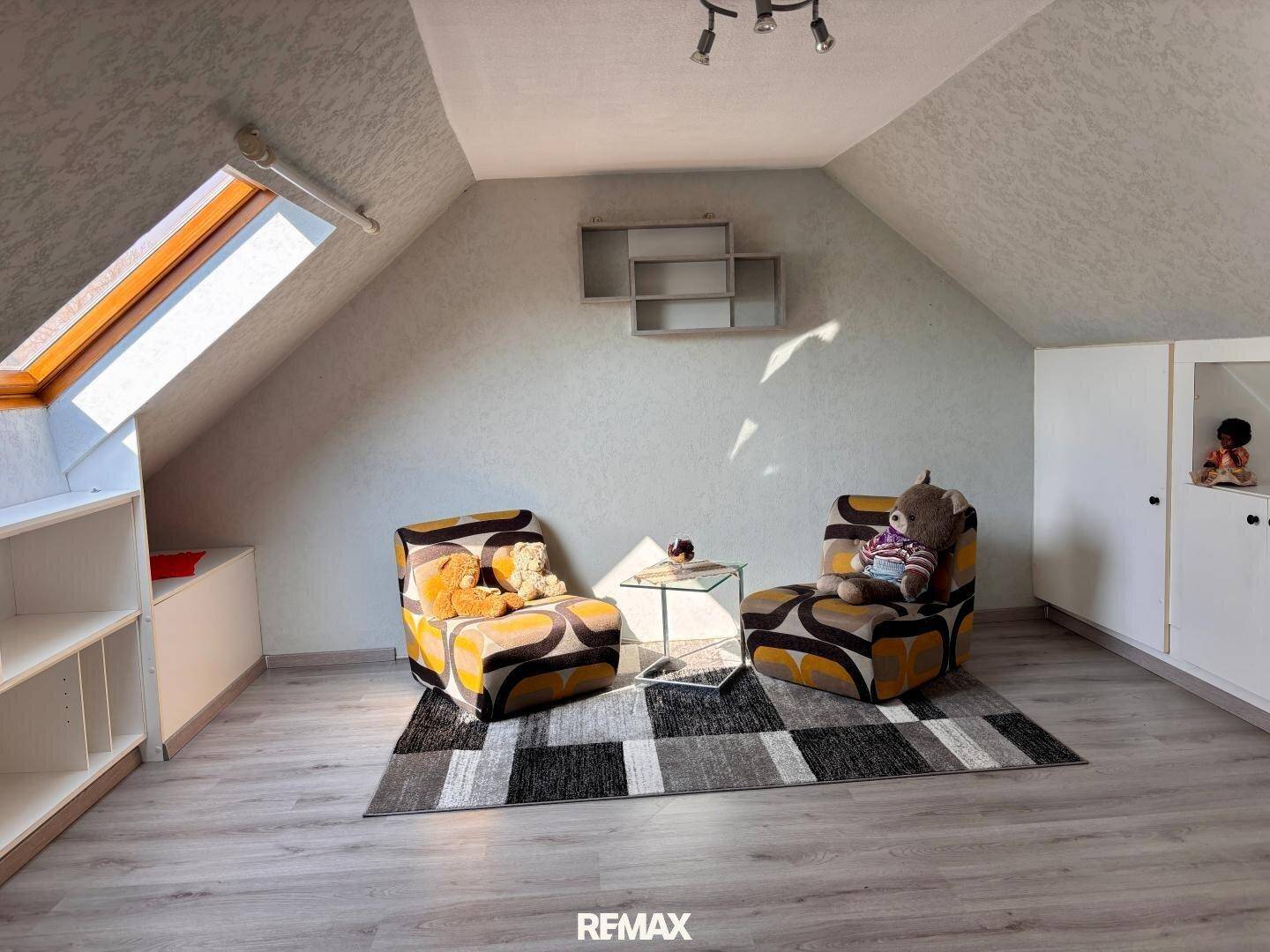 Helles Dachzimmer mit zwei Sesseln und Dachfenster.