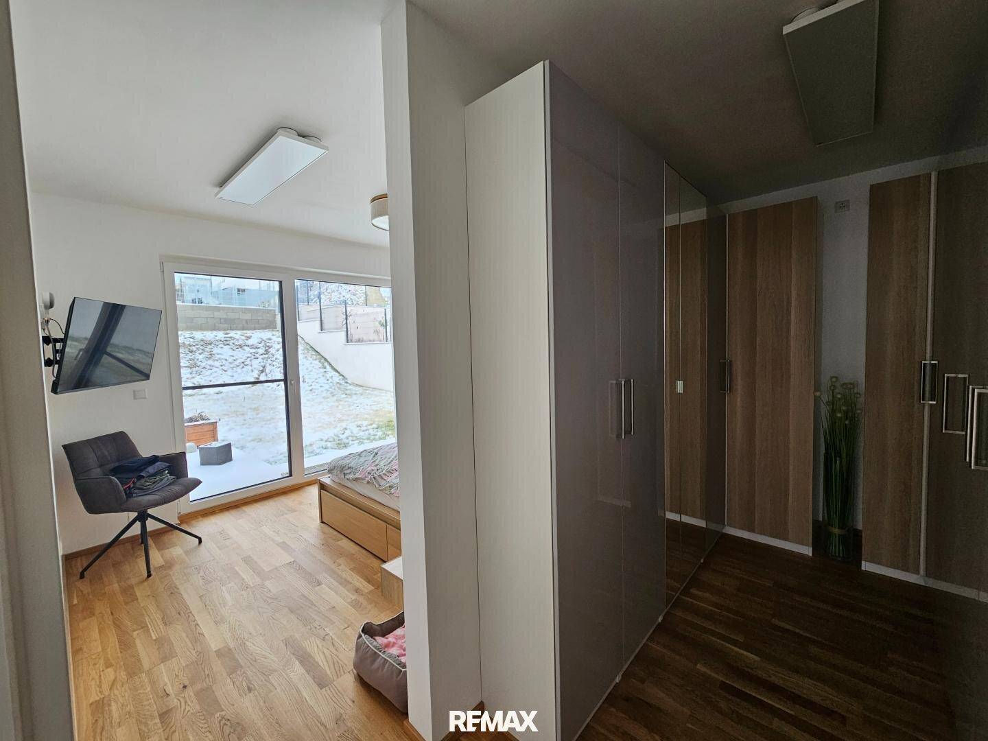 Schlafzimmer mit Holzboden, Einbauschränken und Zugang zu einem Außenbereich.