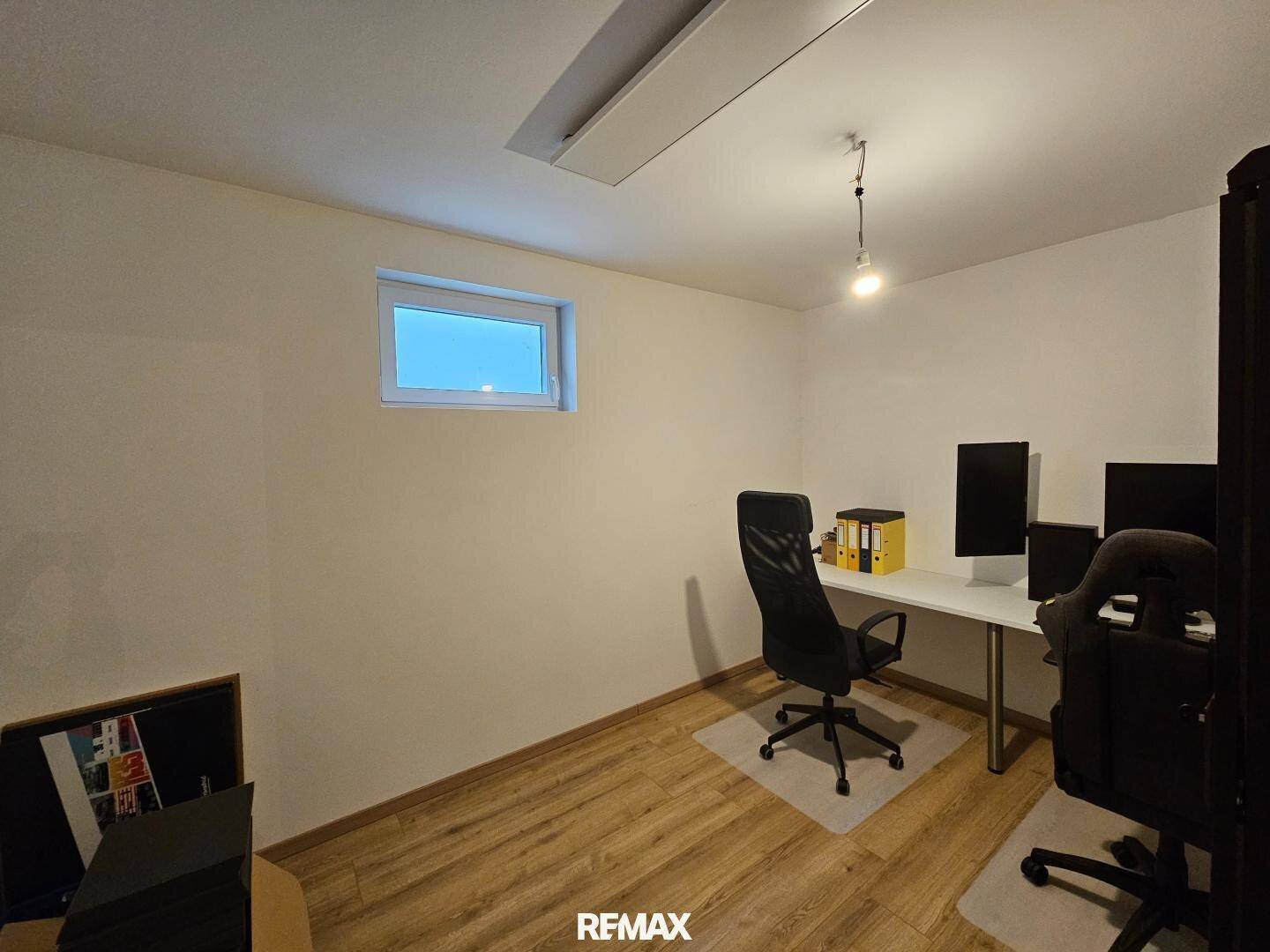 Helles Büro mit Laminatboden und einem kleinen Fenster, ideal für Home-Office-Arbeiten.