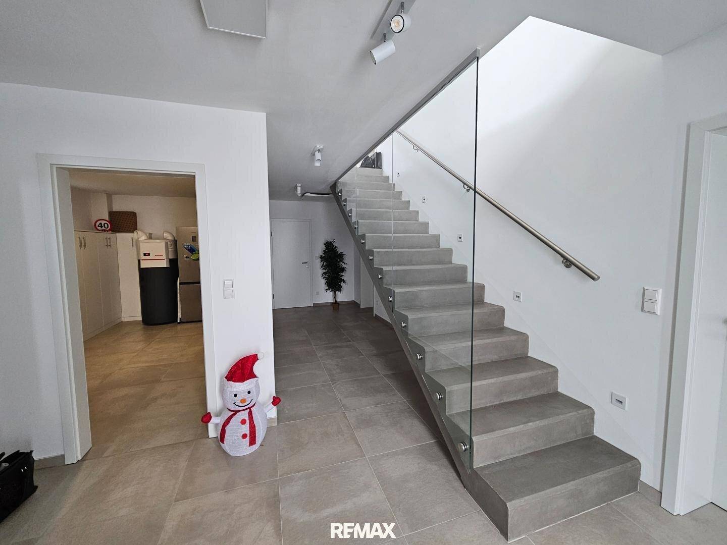 Geräumiger Flur mit Fliesenboden, moderner Treppe und Zugang zu weiteren Räumen.