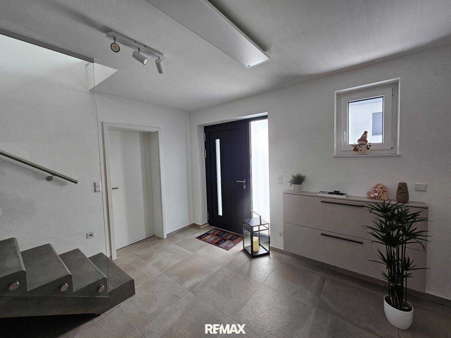 Freundlicher Eingangsbereich mit Fliesenboden, Garderobe und moderner Haustür.