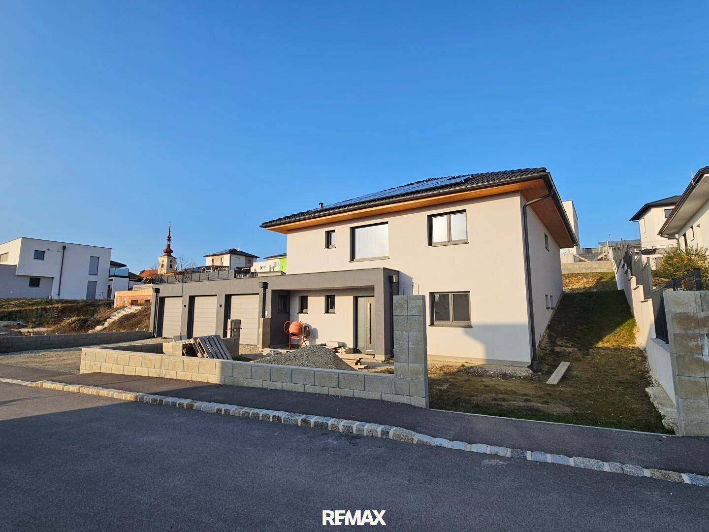 Modernes Einfamilienhaus im Bau mit Garage und vorbereitetem Gartenbereich.
