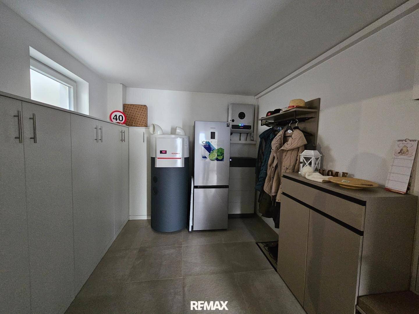 Praktischer Hauswirtschaftsraum mit Einbauschränken, Kühlschrank und Heizungsanlage.