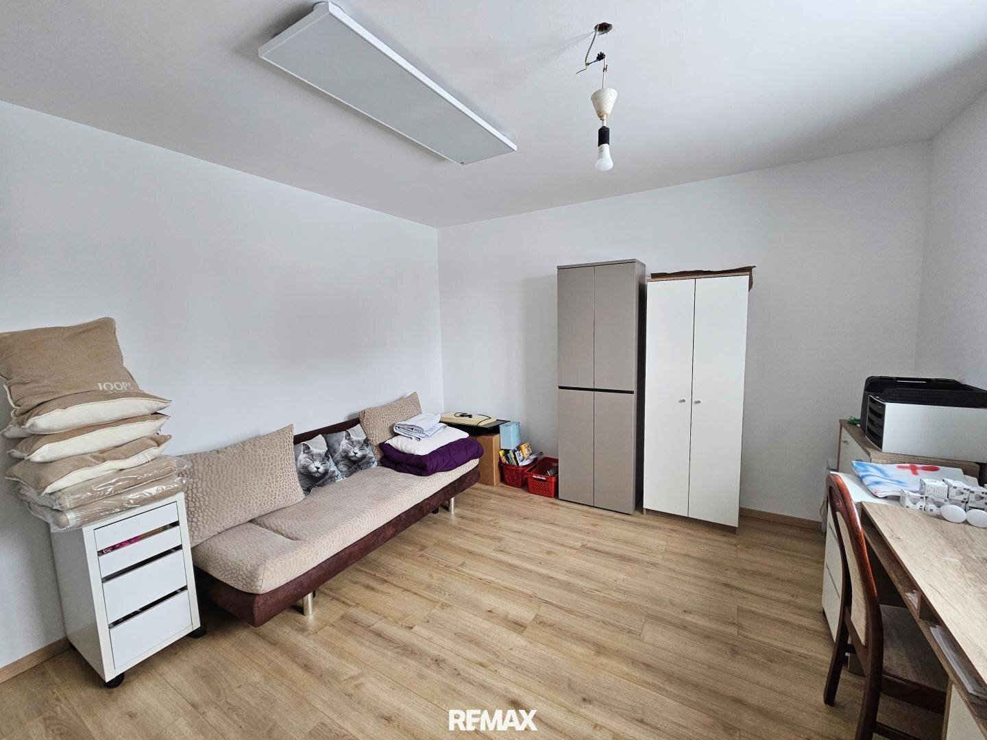 Helles Zimmer mit Laminatboden, Schlafsofa und Kleiderschränken.