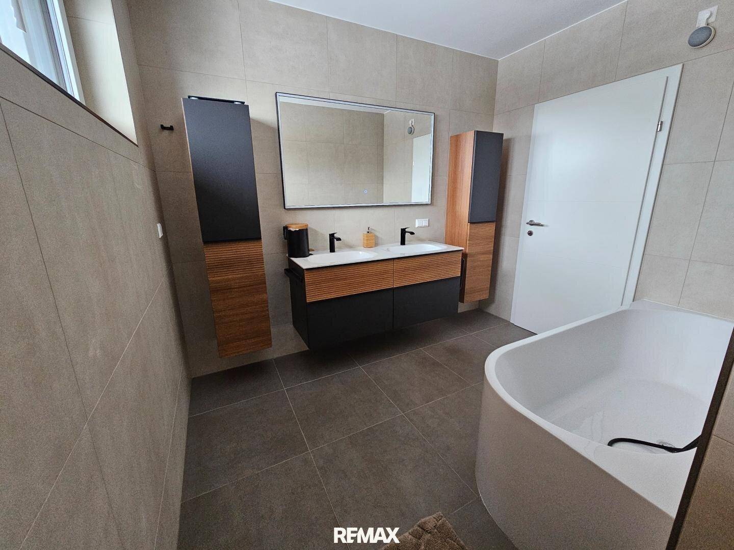 Elegantes Badezimmer mit Doppelwaschbecken, Badewanne und begehbarer Dusche.