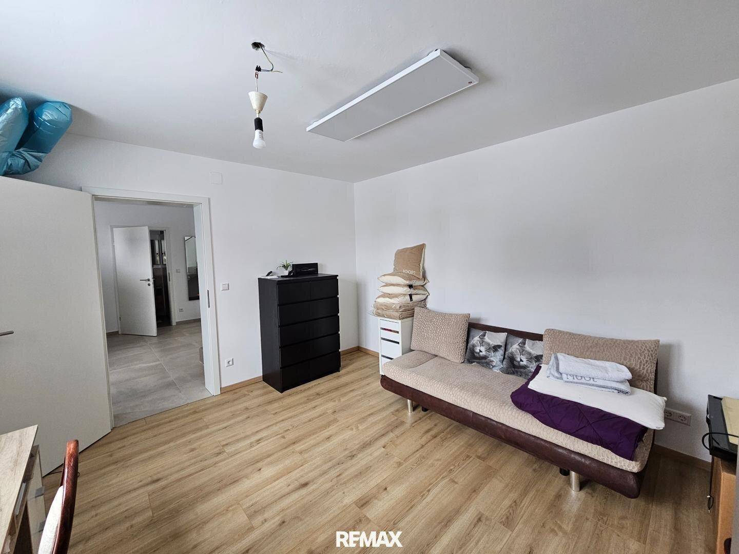 Gemütliches Zimmer mit Laminatboden, Schlafsofa und einfacher Einrichtung.