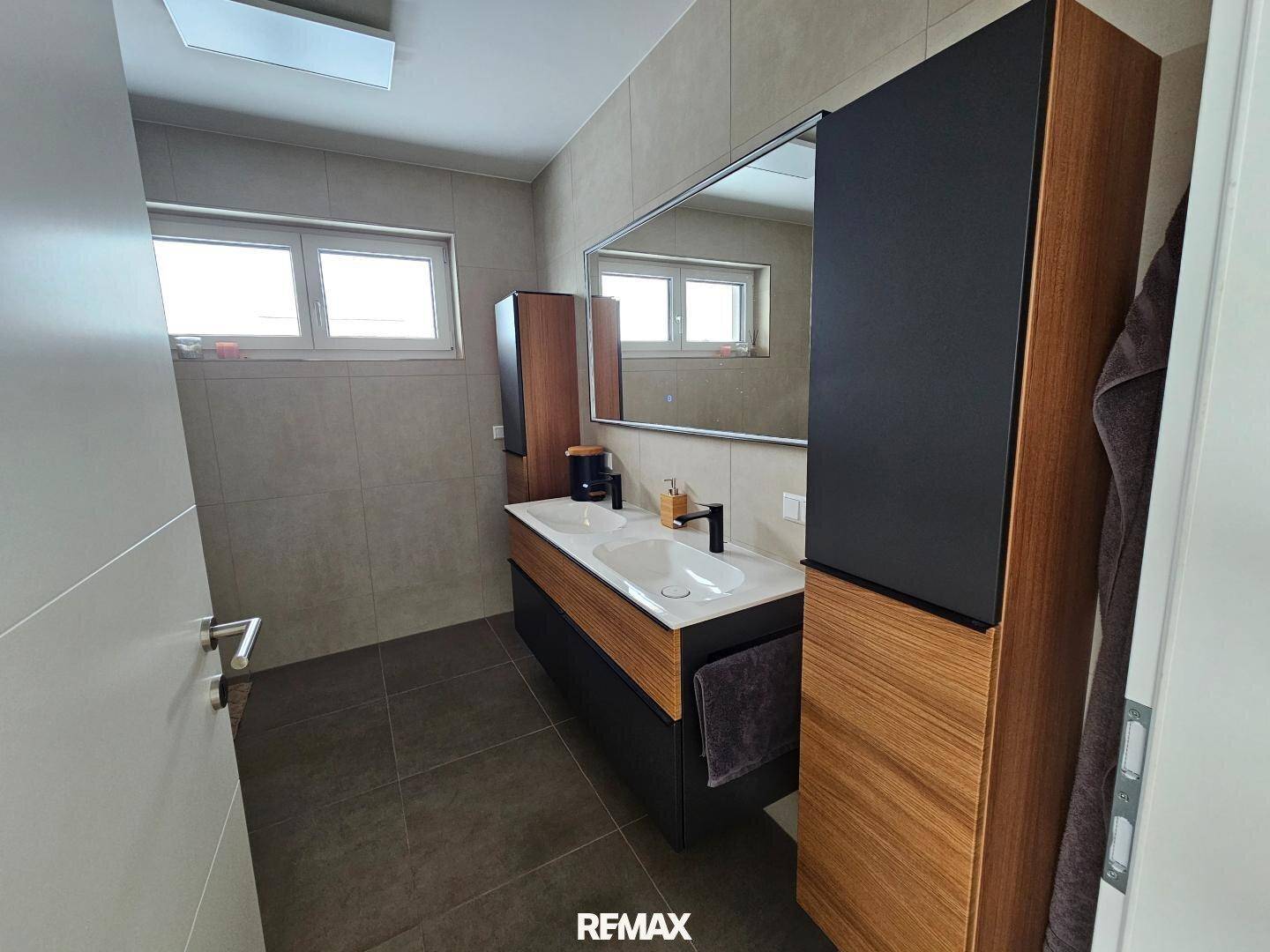 Modernes Badezimmer mit Doppelwaschbecken, großem Spiegel und eleganten Holz-Akzenten.