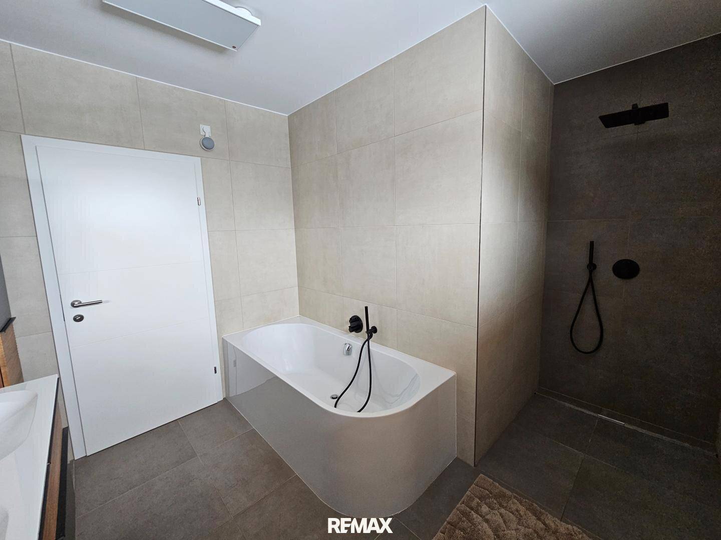 Geräumiges Badezimmer mit moderner Badewanne und begehbarer Dusche.