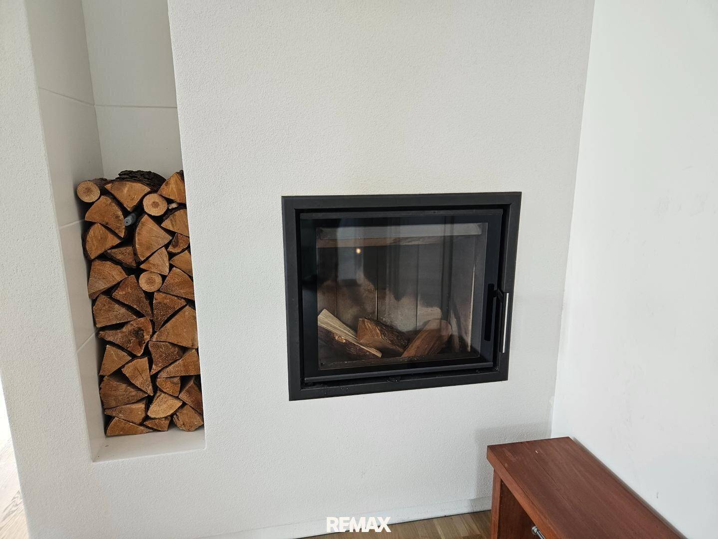 Moderner Einbaukamin mit integriertem Holzscheitlager, schafft eine gemütliche Atmosphäre.