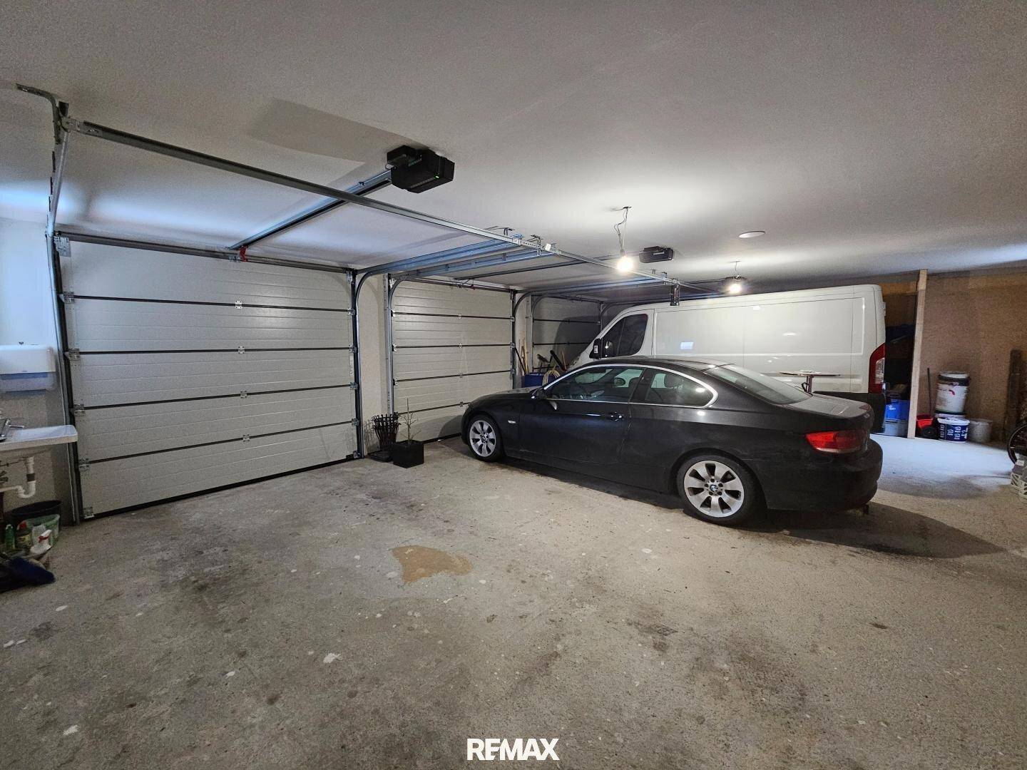 Geräumige Garage mit zwei Sektionaltoren, ausreichend Platz für Fahrzeuge und Lagerung.