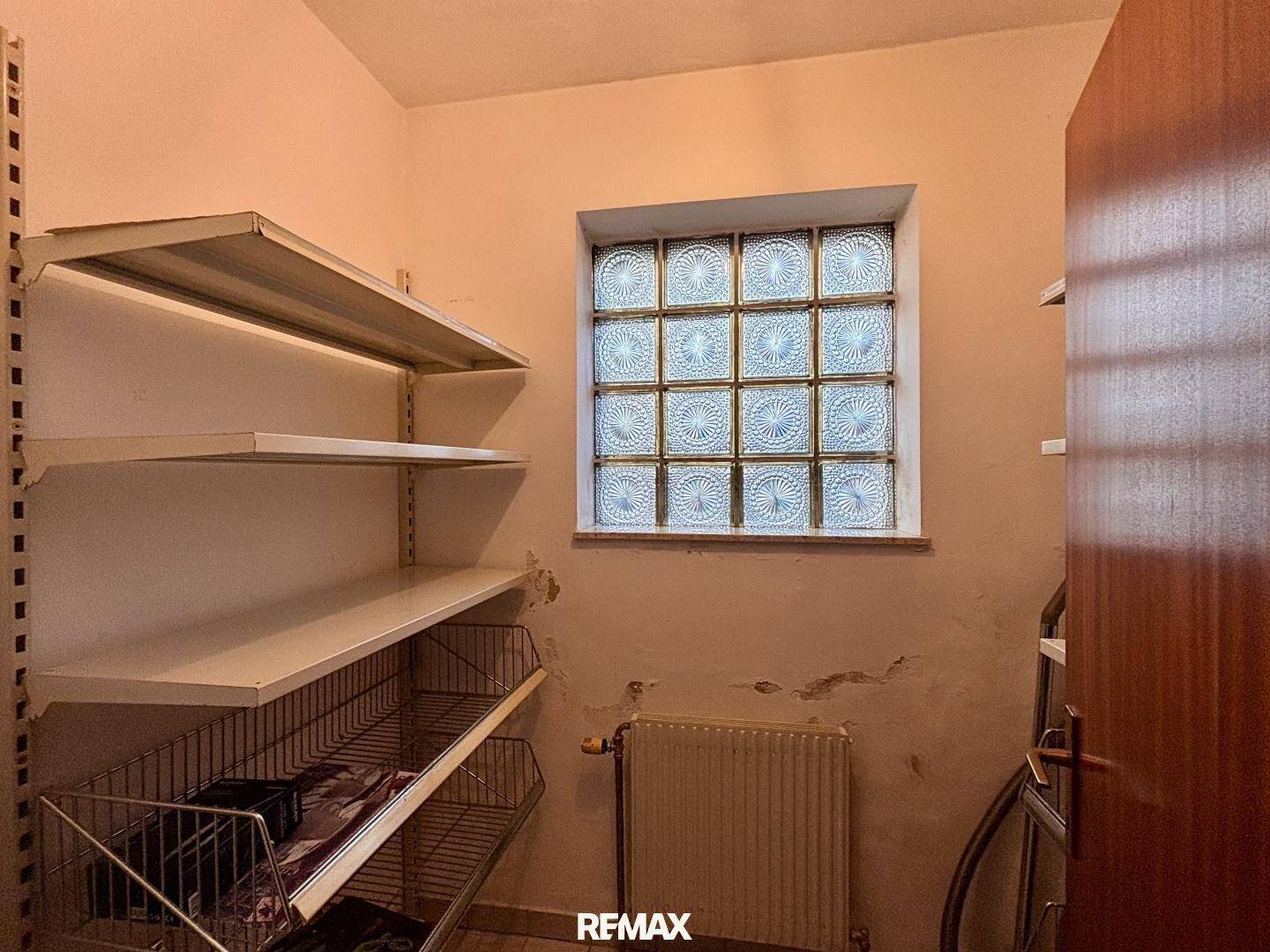 Abstellraum mit Regalen, Heizkörper und Fenster aus Glasbausteinen.