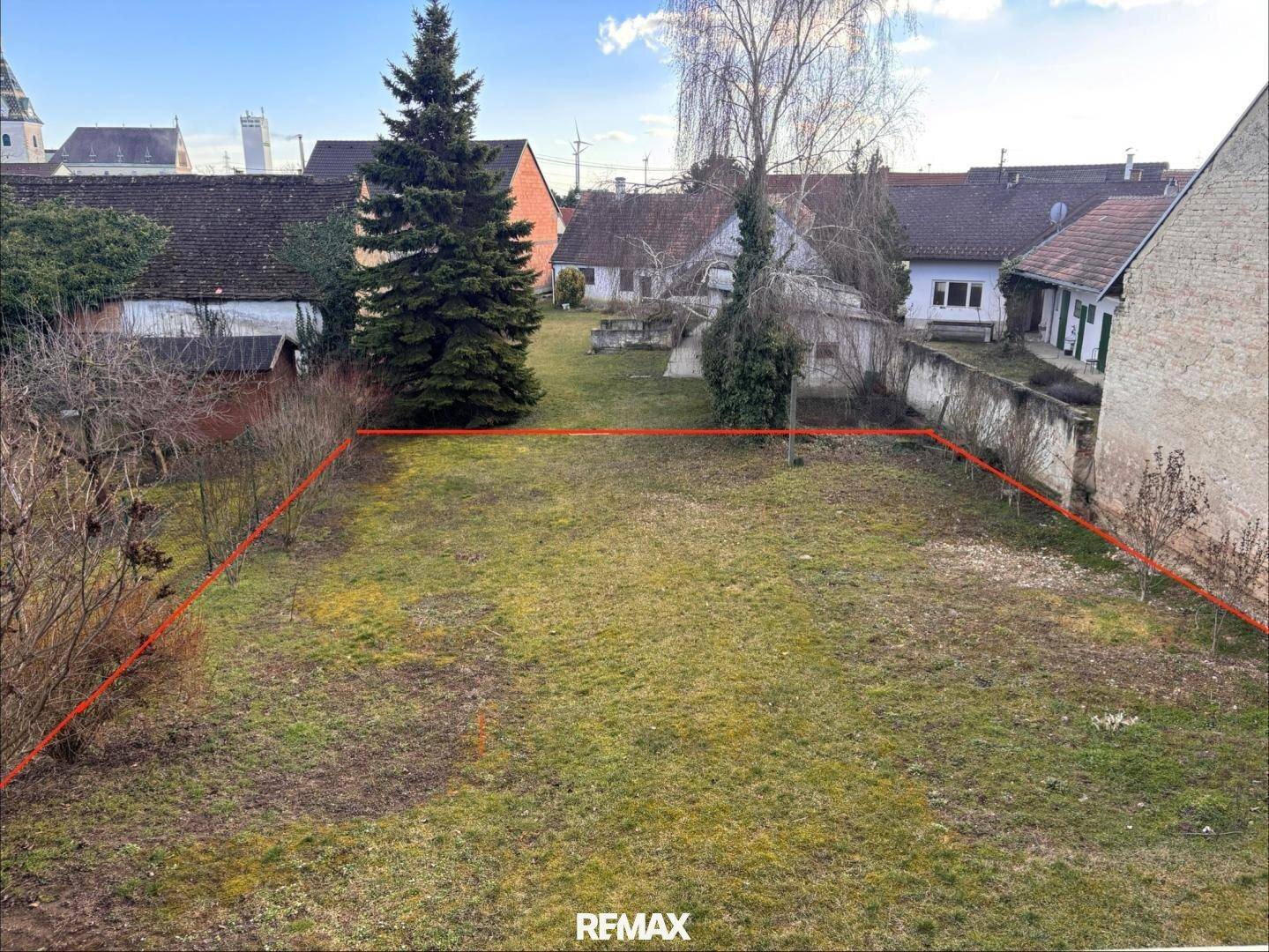 Großer Gartenbereich mit Rasenfläche und Hecken, umrandet von einer roten Linie.