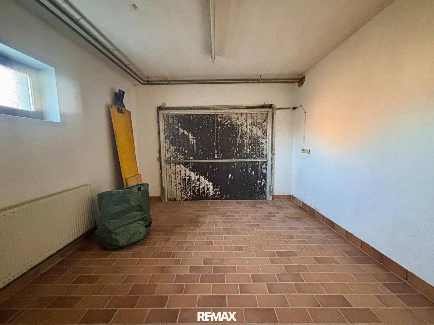 Geräumige Garage im Keller mit Fliesenboden und großem Tor.