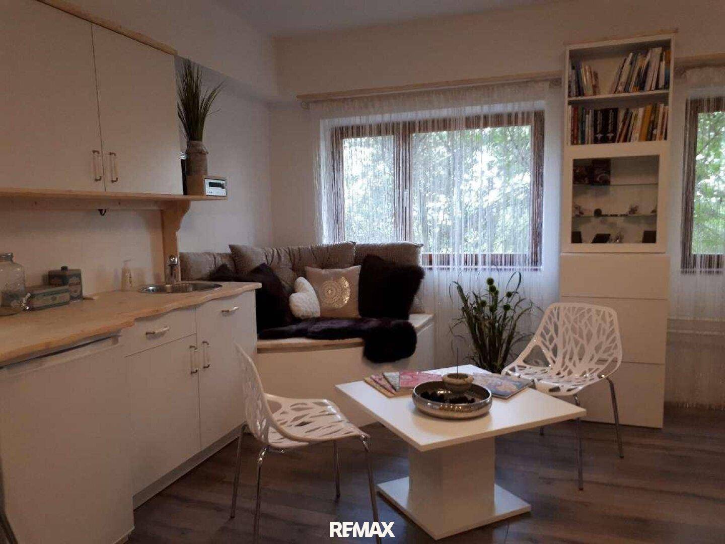 Gemütlicher Wohnbereich mit integrierter Küchenzeile, Fensterbank-Sitzgelegenheit und modernem Dekor.