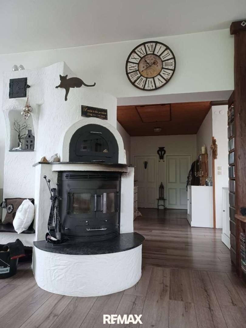 Wohnzimmer mit einem traditionellen Kaminofen und Holzboden, der eine warme Atmosphäre schafft.