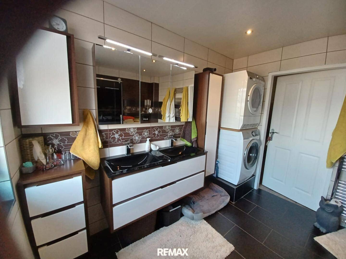 Funktionales Badezimmer mit Doppelwaschbecken, Waschmaschine und Trockner.