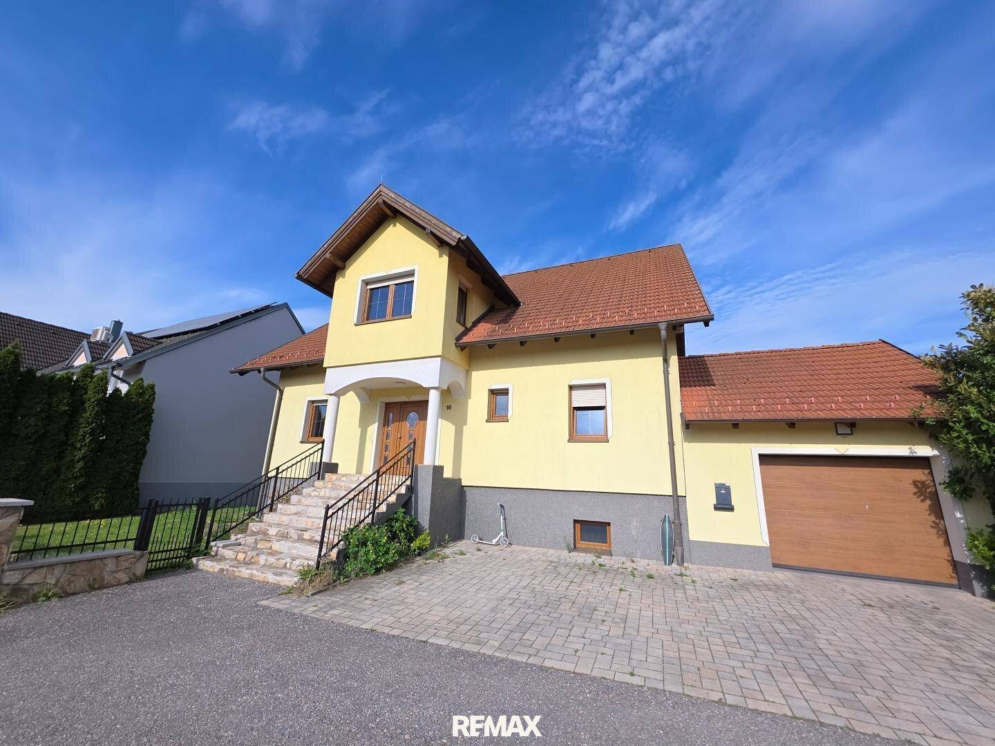 Ansicht des Einfamilienhauses von vorne mit gepflasterter Auffahrt und Garage.