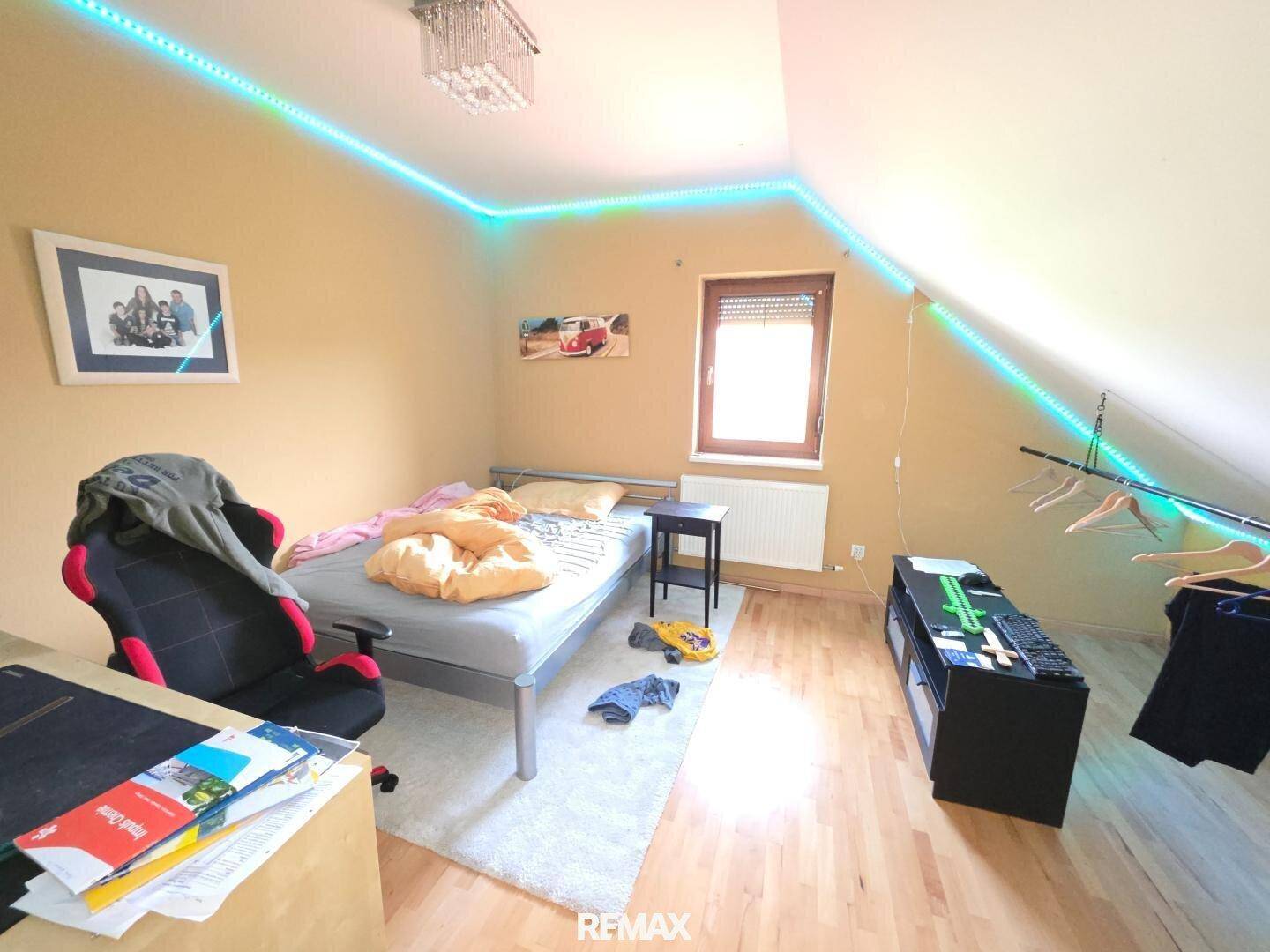 Kinderzimmer mit Holzboden, Dachschräge und farbiger LED-Beleuchtung an der Decke.