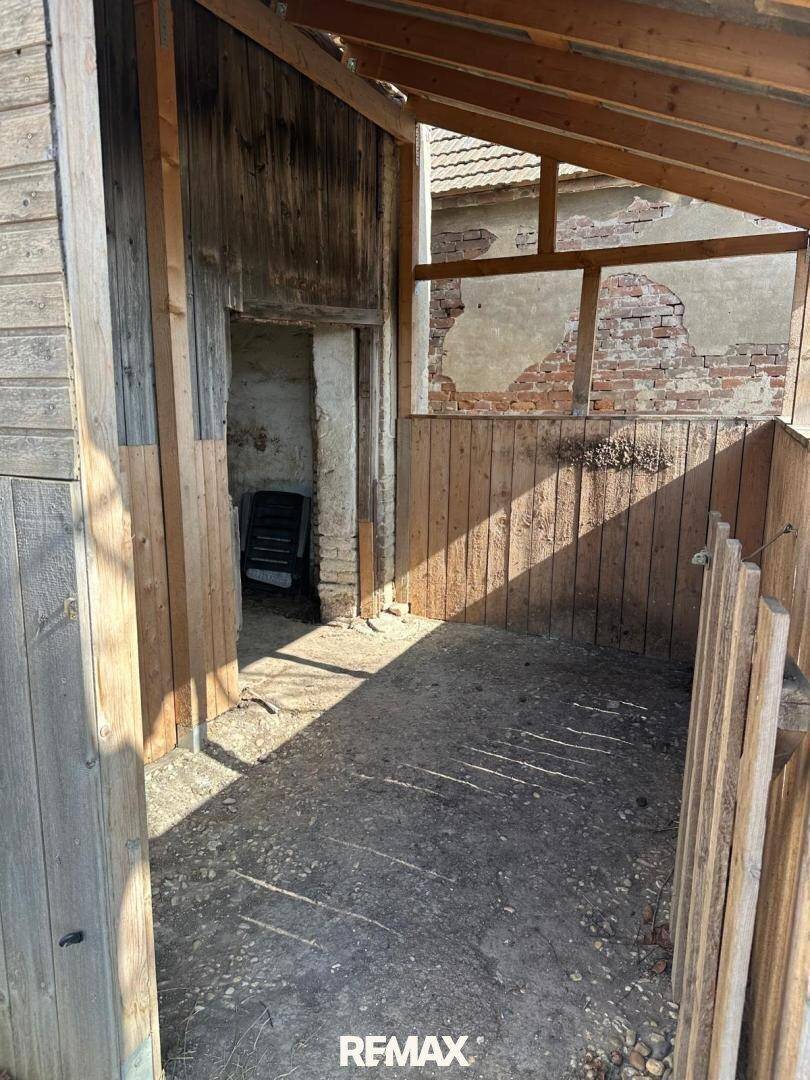 Einfacher Innenraum mit Holzwänden und Betonboden, ideal als Abstellraum oder Werkstatt.