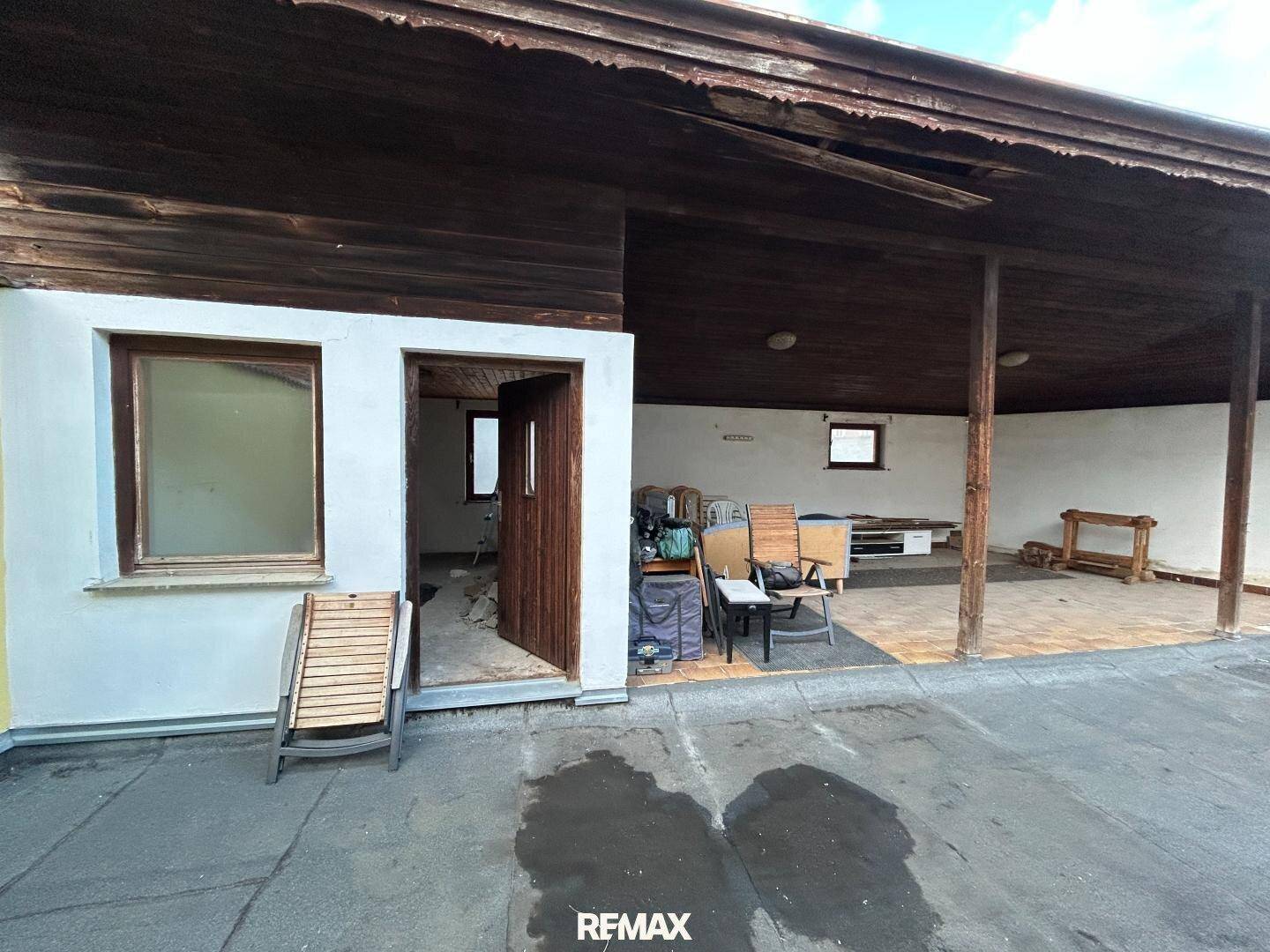 Überdachte Terrasse mit Holzboden und Blick auf den Hof, ideal für entspannte Stunden.