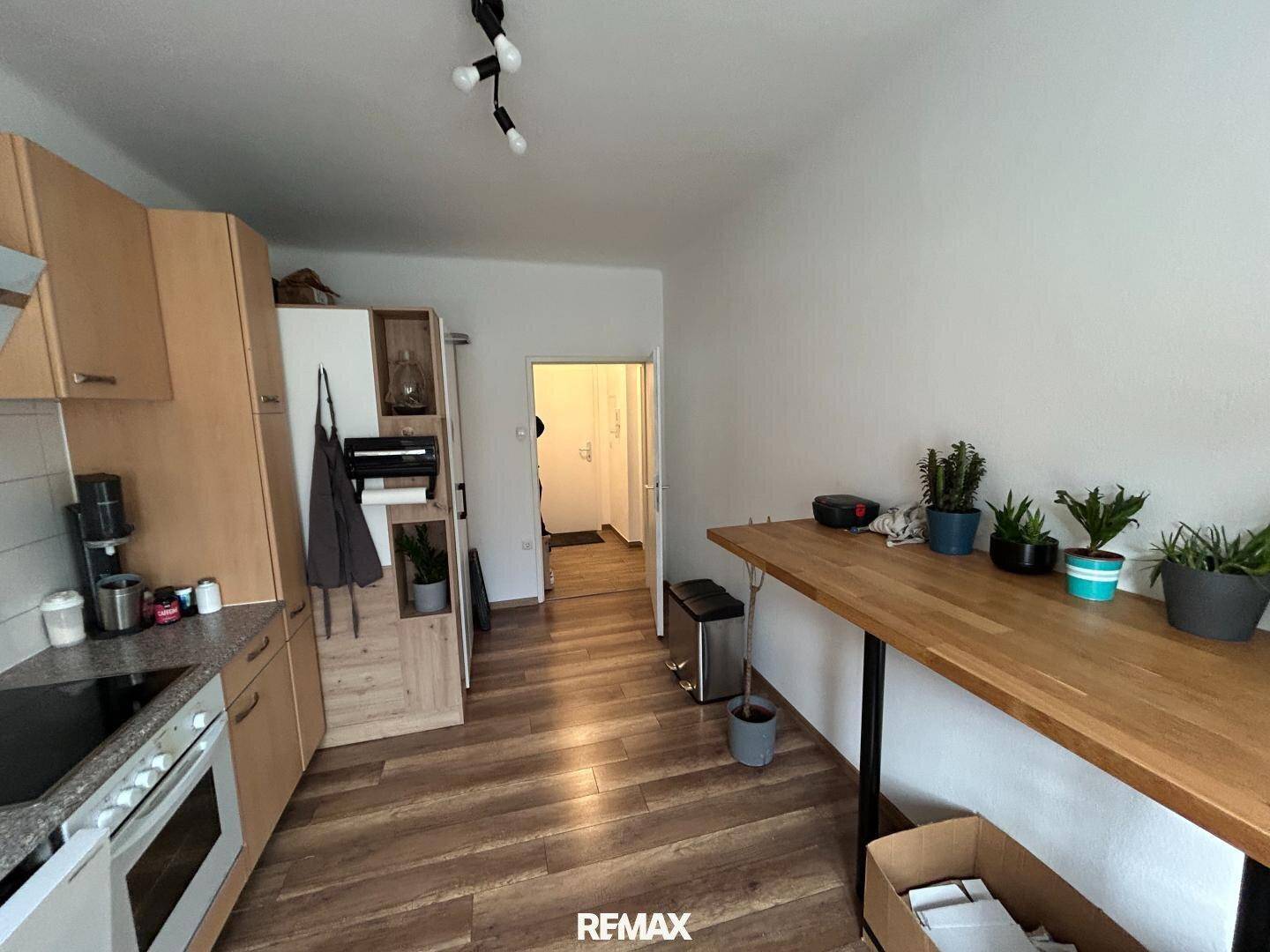 Funktionale Küche mit Holzboden, Einbauschränken und einem langen Holztresen.