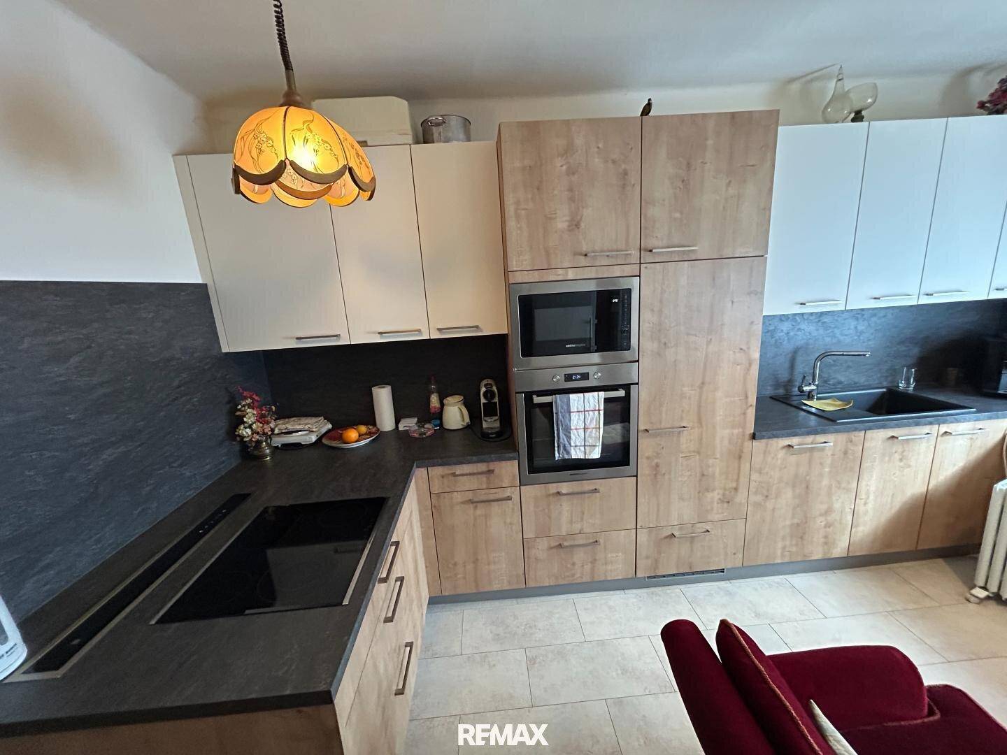 Moderne Einbauküche mit Holz- und weißen Fronten, integrierten Geräten und Fliesenboden.