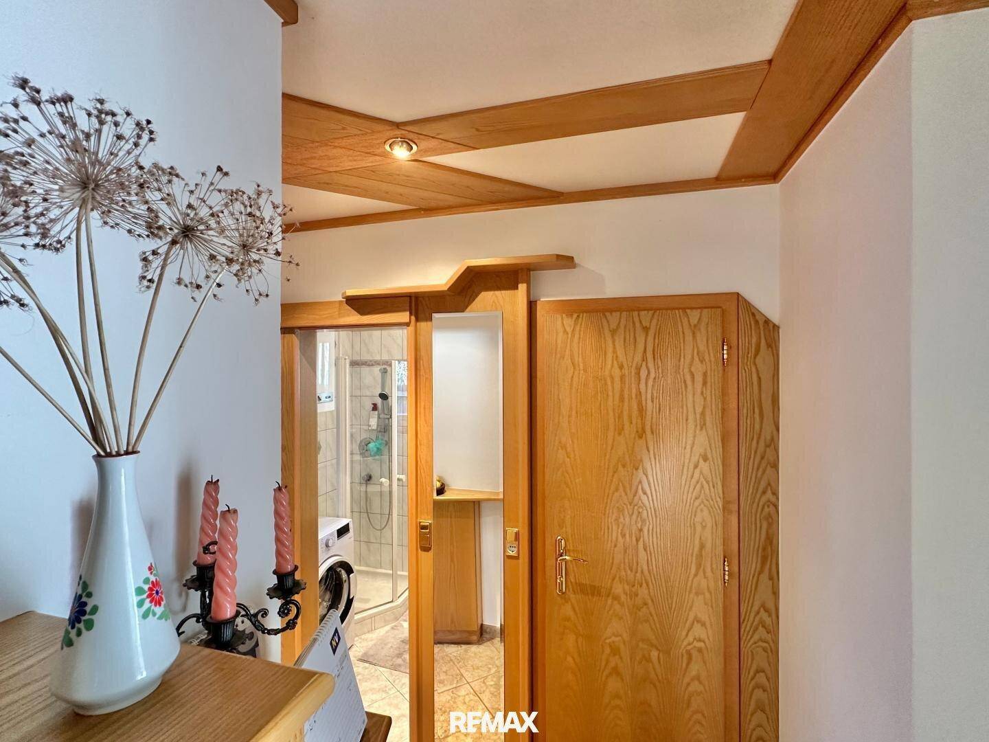 Flur mit Holzbalkendecke und Zugang zu einem Badezimmer mit Waschmaschine.