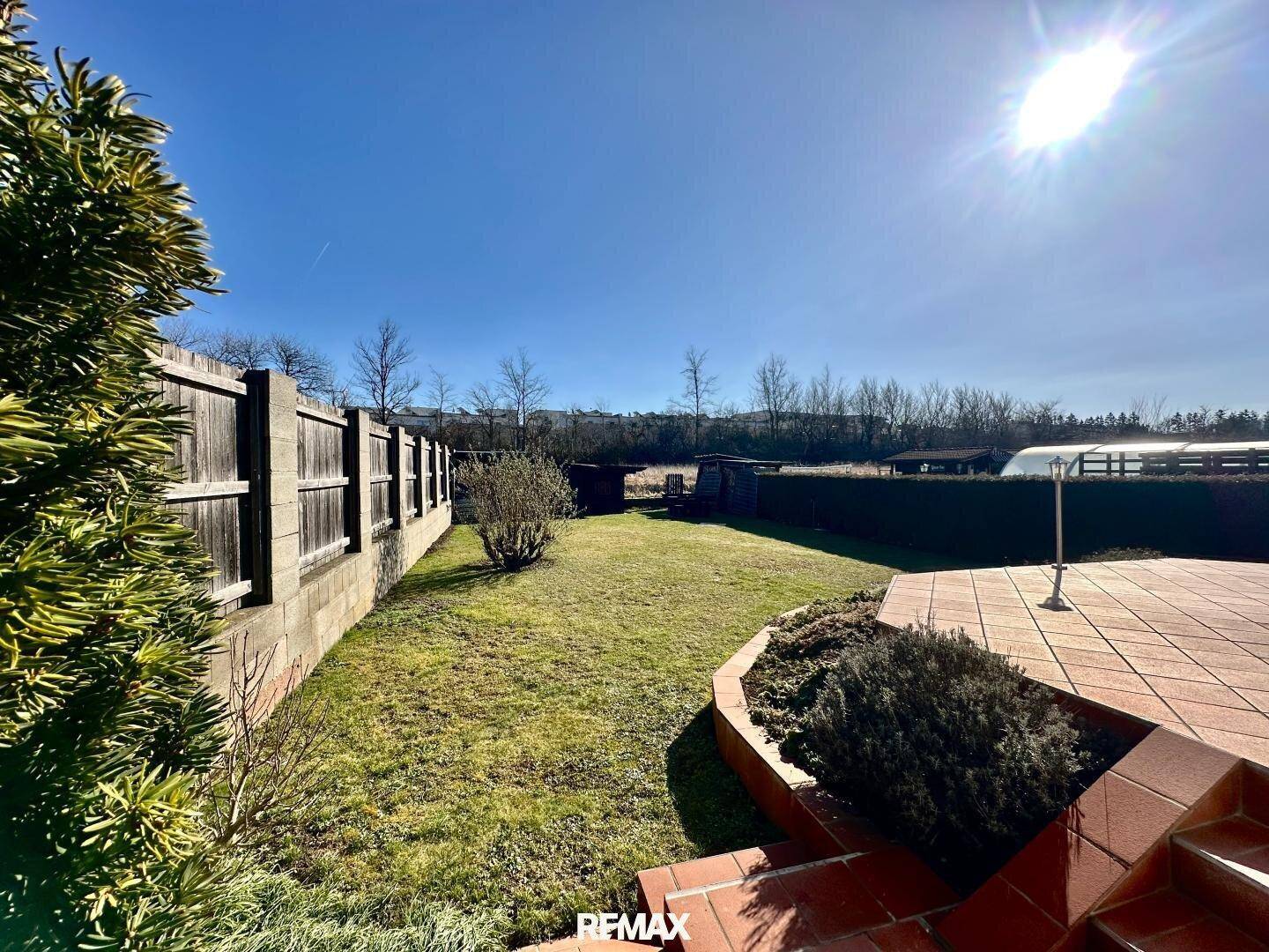 Weitläufiger Garten mit Rasenfläche, Holzzaun und freiem Blick in die Natur.