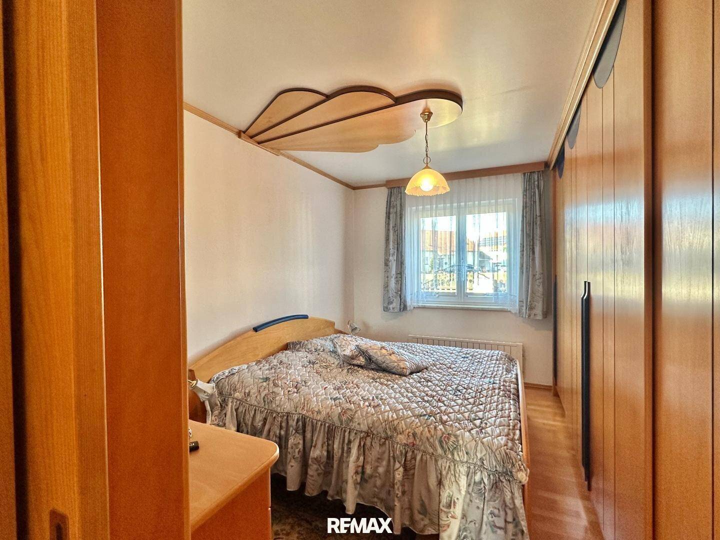 Schlafzimmer mit Doppelbett, großem Holzschrank und Fenster für Tageslicht.