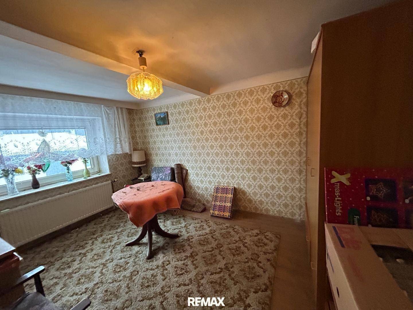 Gemütliches Zimmer mit Teppichboden, gemusterter Tapete und einem kleinen Tisch.
