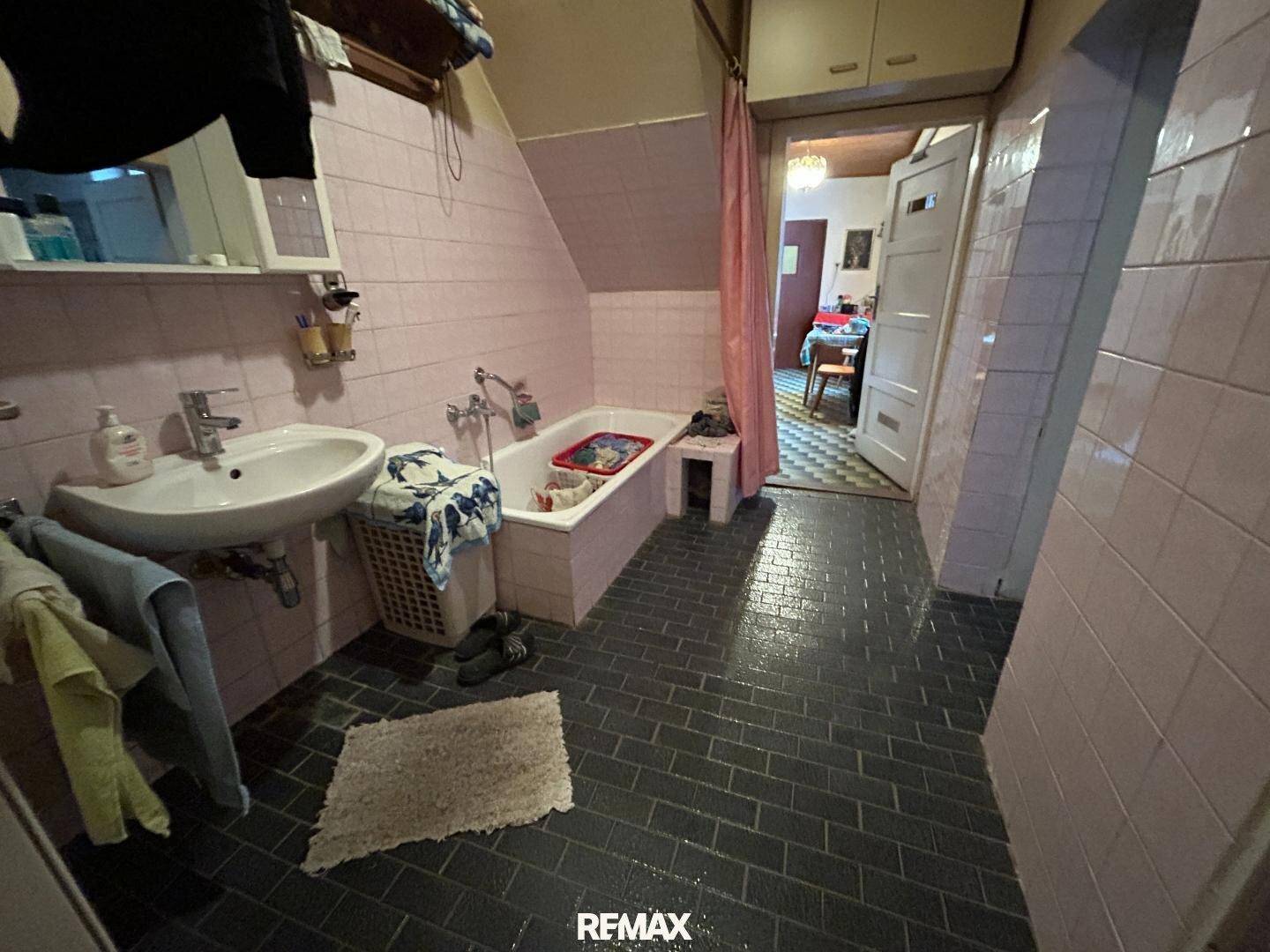 Badezimmer mit rosa Fliesen, Badewanne und Waschbecken, typisch für die 80er Jahre.