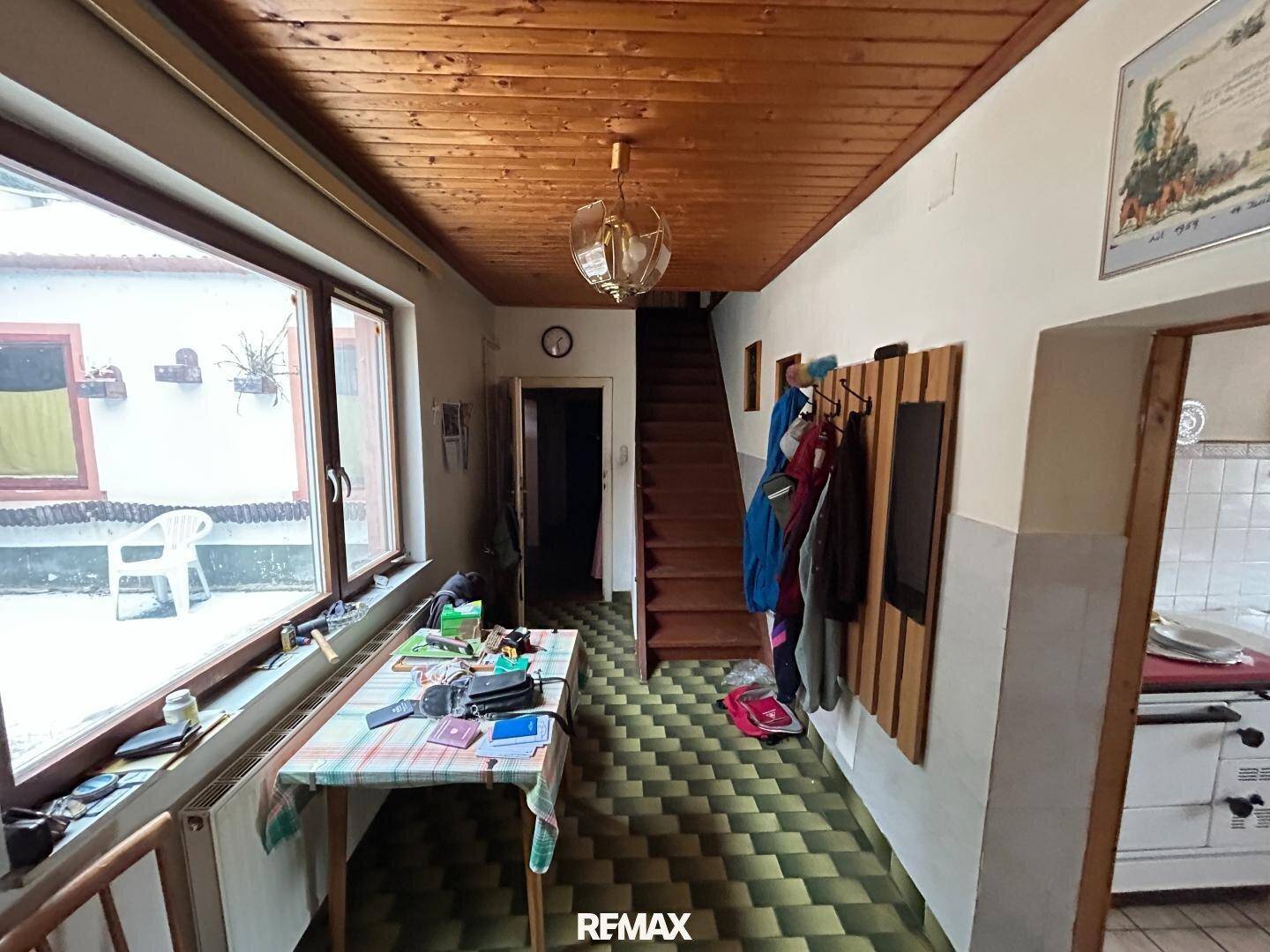Flur mit Holzdecke, gemustertem Fliesenboden und Garderobe.