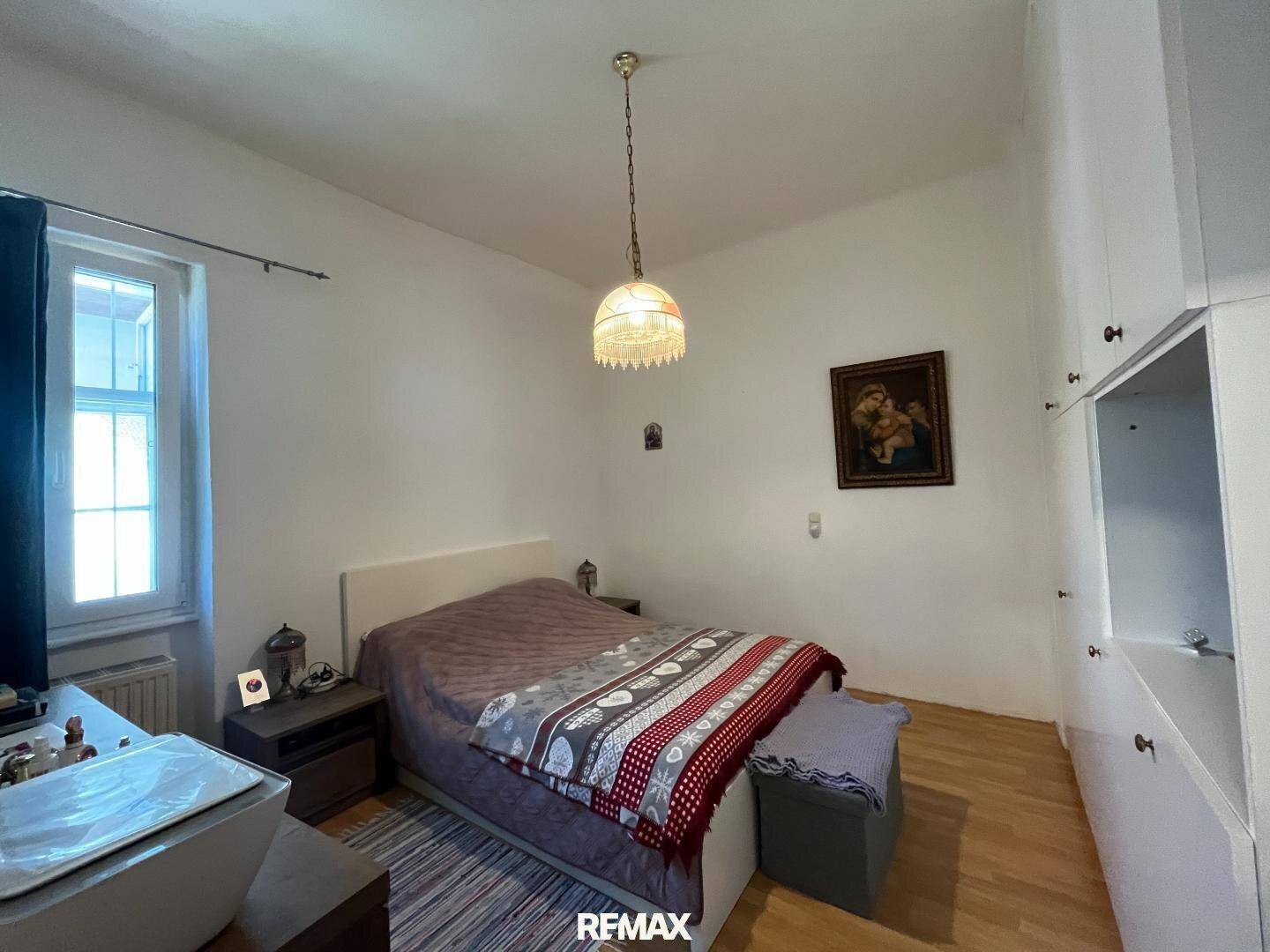 Schlafzimmer mit Doppelbett, Holzfußboden und weißem Kleiderschrank, hell und gemütlich.