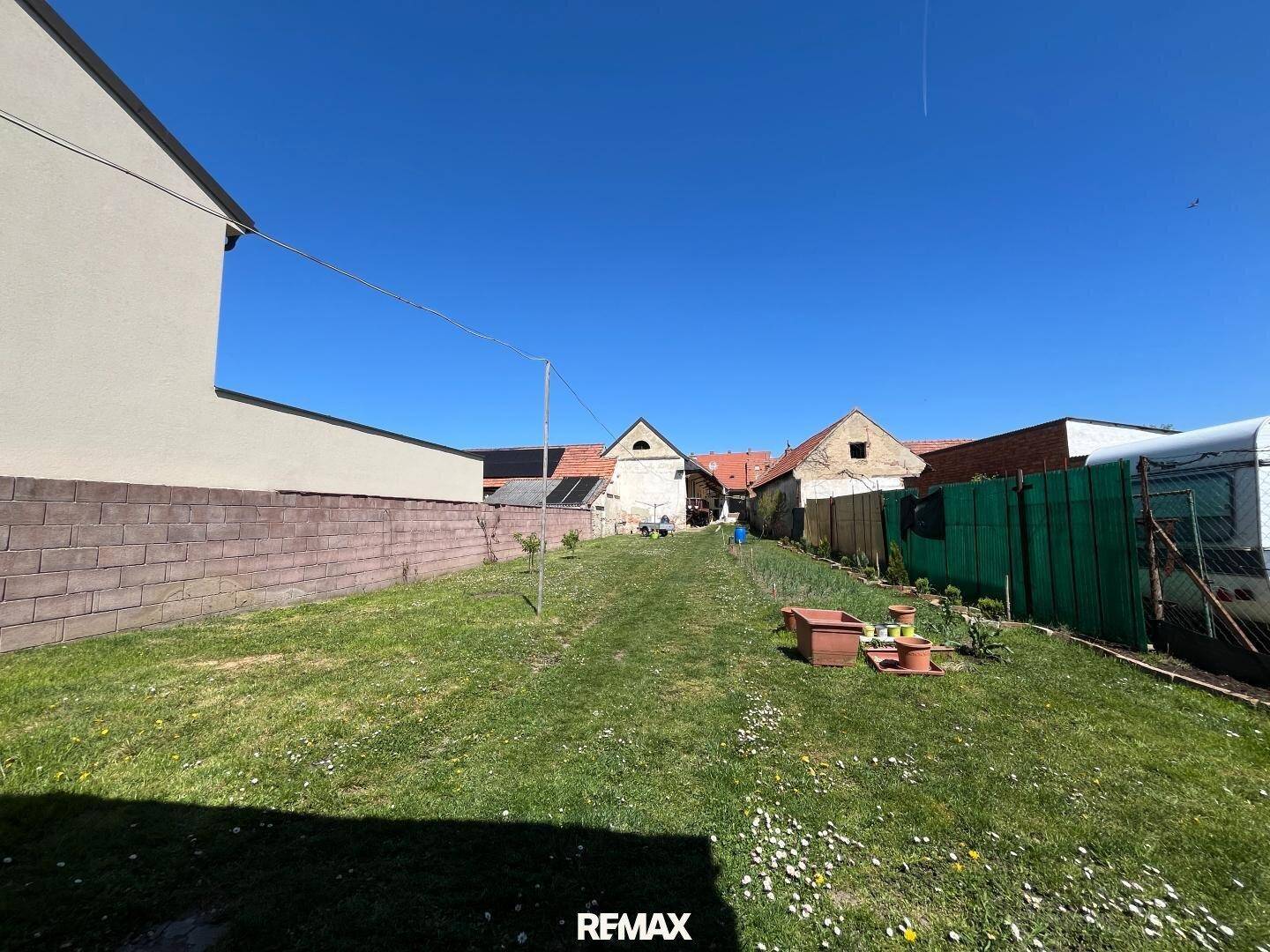 Weitläufiger Garten mit Rasenfläche und Blick auf benachbarte Gebäude, ideal für Erholung.