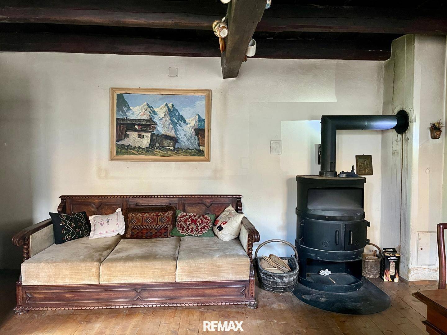 Gemütliches Wohnzimmer mit Holzboden, einem traditionellen Holzofen und einer rustikalen Holzbank.