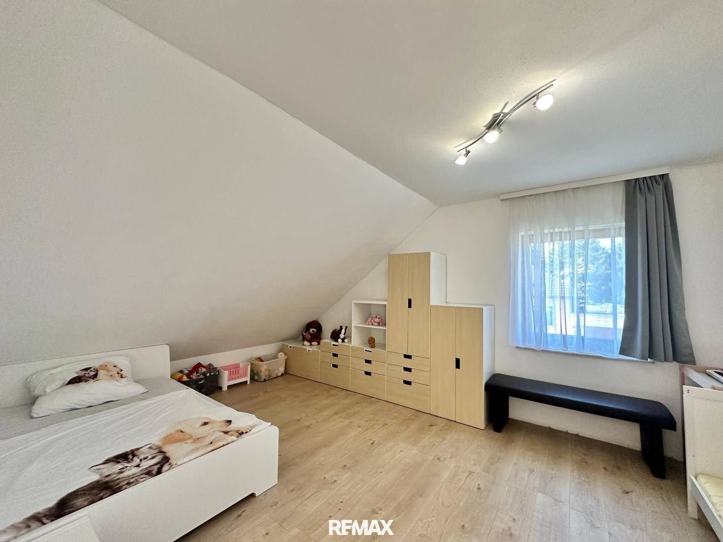 Kinderzimmer im Dachgeschoss mit Bett, Stauraum und Dachschräge.