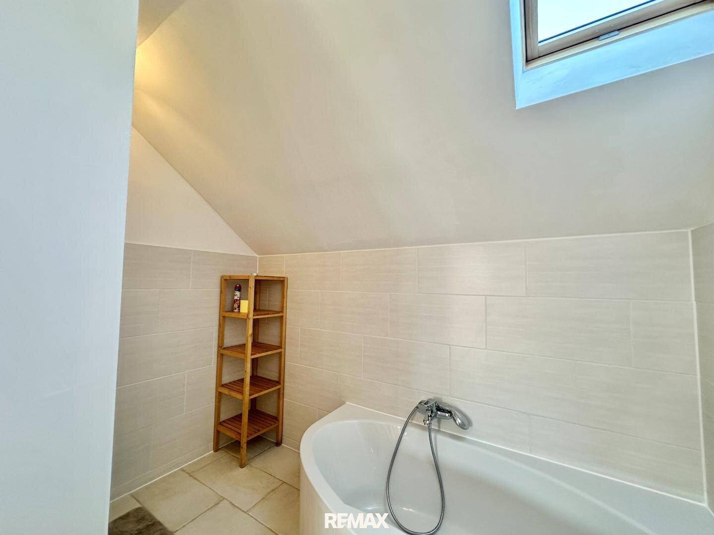 Badewannenbereich im Dachgeschoss-Badezimmer mit hellem Dachfenster.