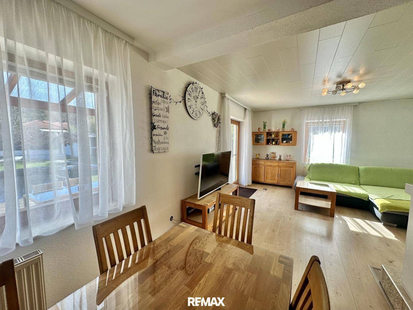 Heller Wohn-Essbereich mit Esstisch, Sofa und großen Fenstern zum Garten.