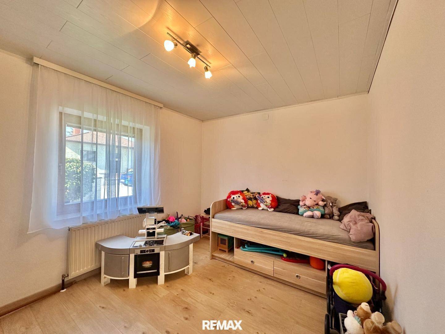 Kinderzimmer mit Bett, Schreibtisch und Fenster, hell und freundlich gestaltet.