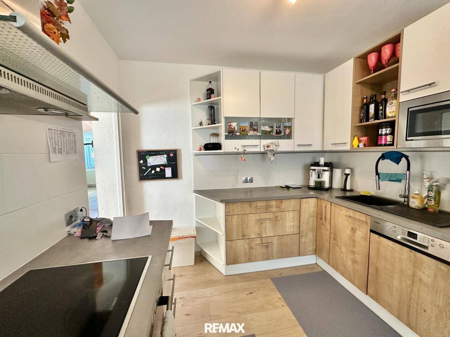 Funktionale Küche mit Holz- und Weißfronten, Induktionskochfeld und Spülbecken.