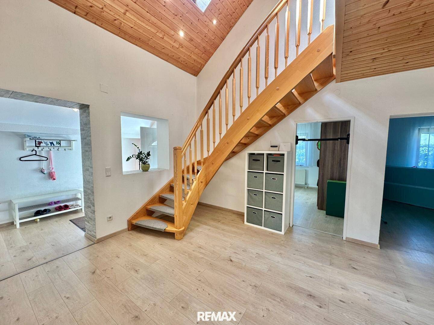 Heller Flur mit Holztreppe zum Obergeschoss und Zugang zu weiteren Räumen.