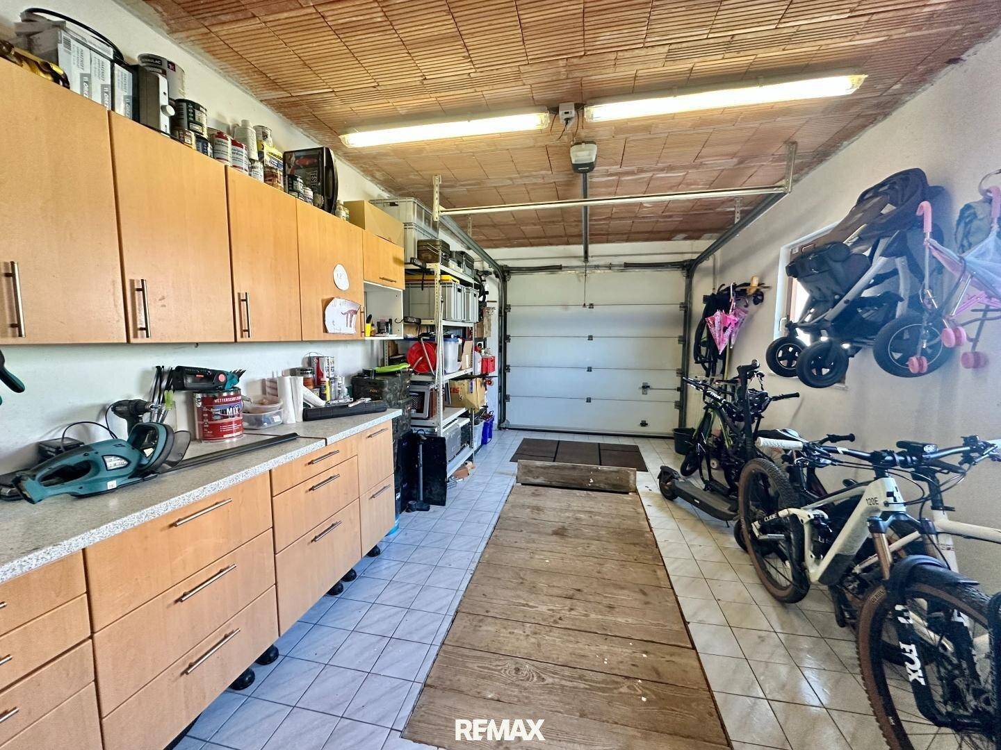 Geräumige Garage mit Werkbank, Lagerschränken und Platz für Fahrräder.