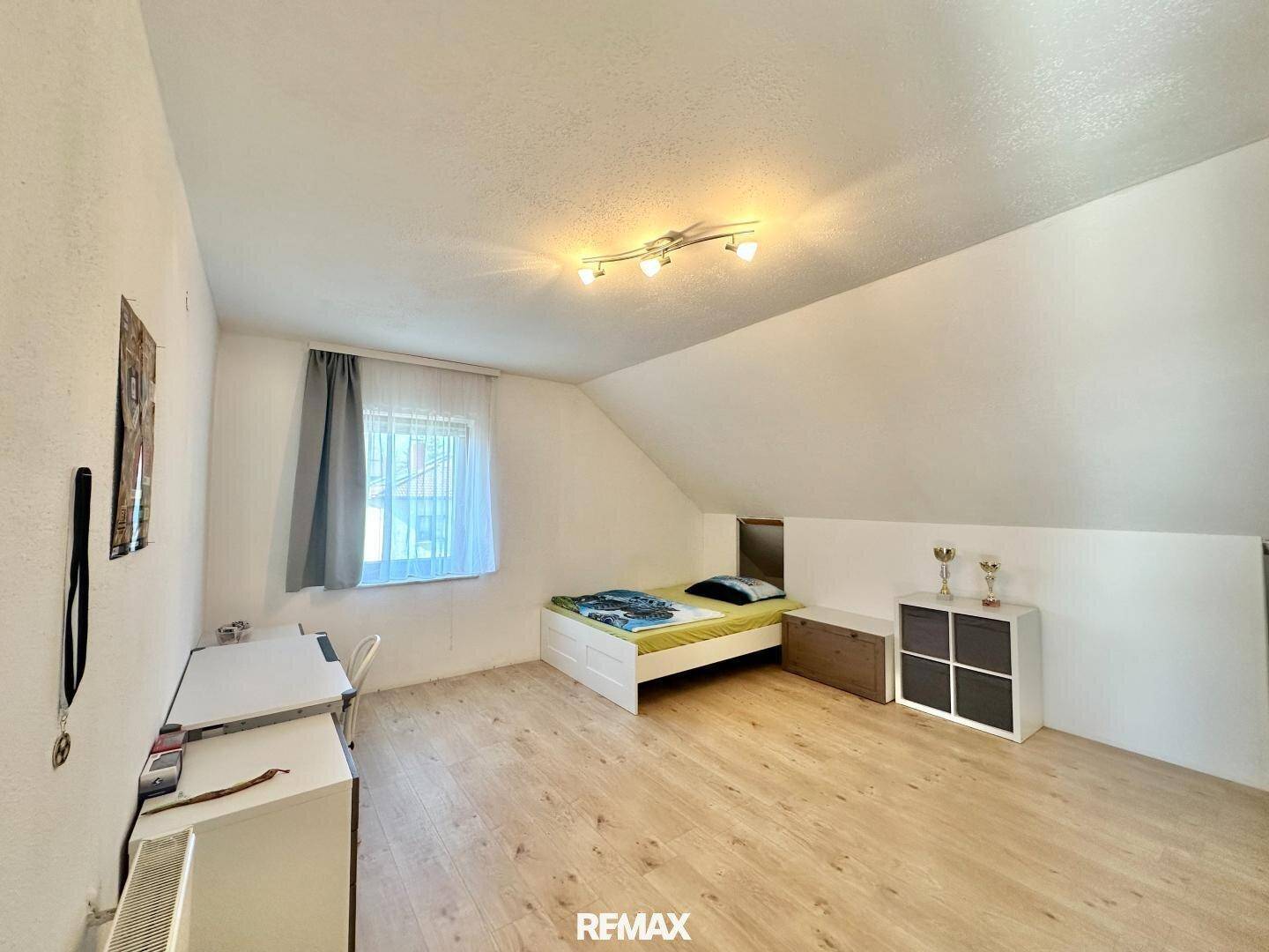 Gemütliches Schlafzimmer im Dachgeschoss mit Bett, Schreibtisch und Dachschräge.