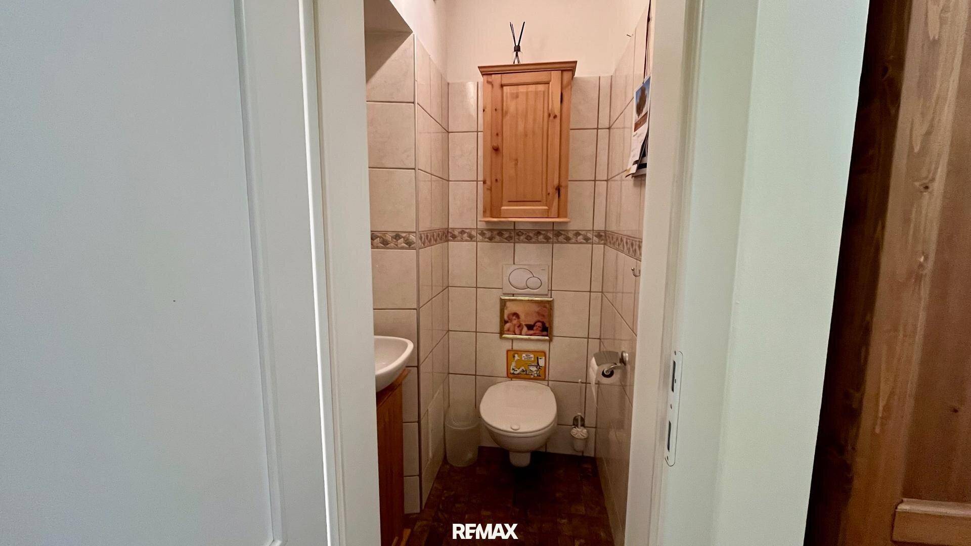 Kleines Gäste-WC mit Waschbecken und Wandfliesen in neutralen Farben.
