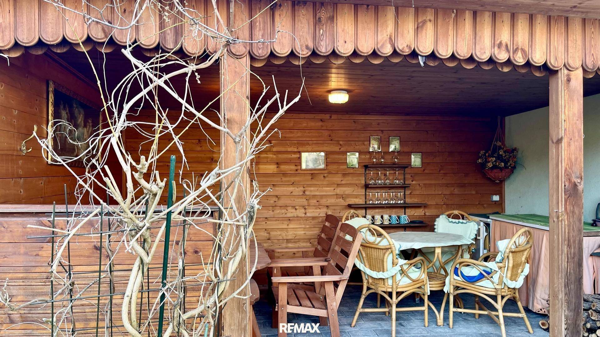 Überdachte Holzterrasse mit Gartenmöbeln und rustikalem Charme.